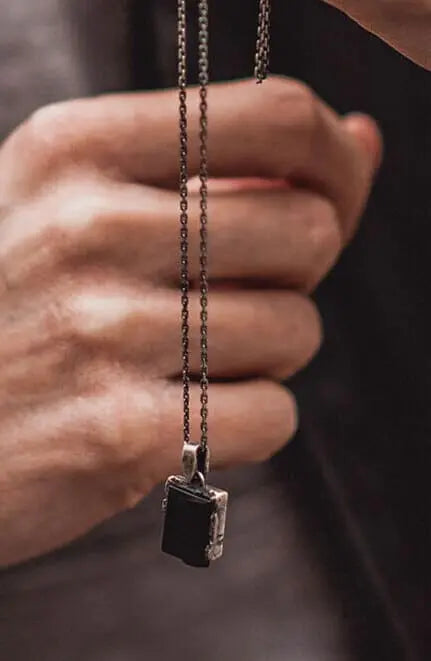 mão do homem que usa uma jaqueta marrom, segundo um colar preto